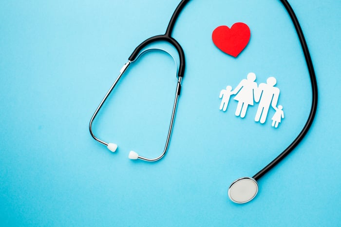 Stethoscope with heart and family icons on blue background symbolizing modern patient journey from online search to healthcare consultation.