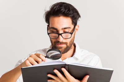 "Doctor closely examining a book with a magnifying glass, symbolizing attention to detail and fact-checking."