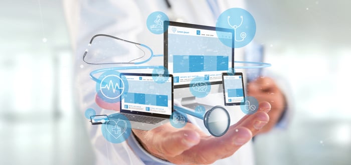 Doctor holding digital healthcare interface with stethoscope, mobile, tablet, and laptop icons representing responsive and secure medical website design.