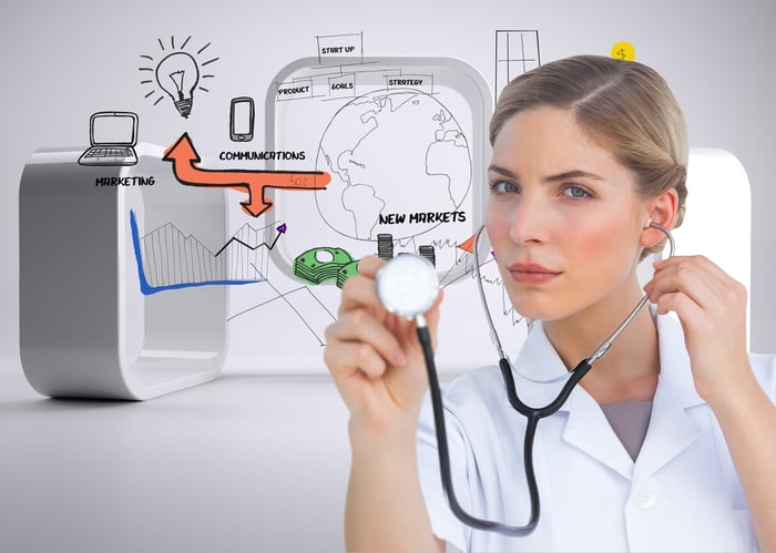 Female doctor using a stethoscope to assess digital marketing strategies for doctors, symbolizing the healthcare marketing for patient acquisition.