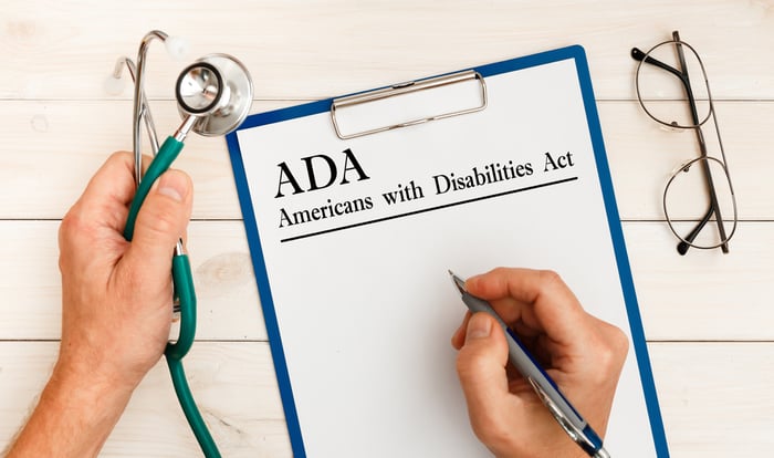 Close-up of a doctor holding a stethoscope and clipboard with “ADA – Americans with Disabilities Act” written on it, symbolizing ADA compliance and inclusive medical website design for all patients.