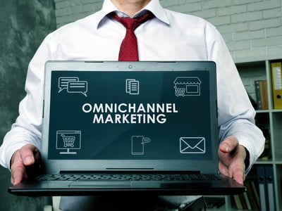 Professional holding a laptop displaying “Omnichannel Marketing,” representing a seamless omnichannel patient journey through integrated healthcare marketing strategies.
