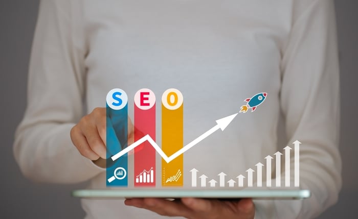 Doctor using a tablet with illustrated SEO bars, growth charts, and a rocket icon—representing the need for healthcare professionals to adapt SEO strategies for AI-driven search in medical website development.