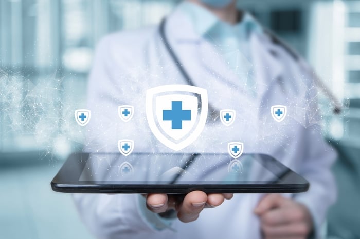 Doctor holding a tablet with a digital healthcare shield icon, representing the importance of digital marketing for doctors in building trust, visibility, and patient engagement.