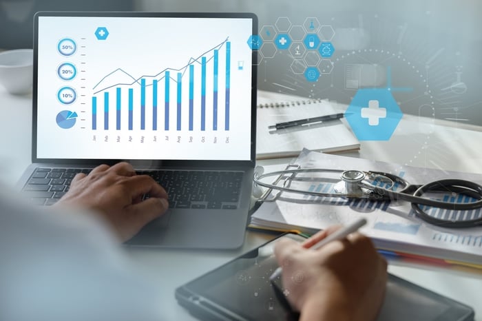 Doctor analyzing growth charts on a laptop with medical icons and a stethoscope nearby — symbolizing how PracticeBeat’s Medical SEO services drive measurable patient growth and revenue.
