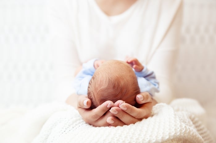 Close-up of a millennial parent gently cradling a newborn baby in their hands, symbolizing modern parenting values, care, and the unique perspectives of today’s generation of parents.