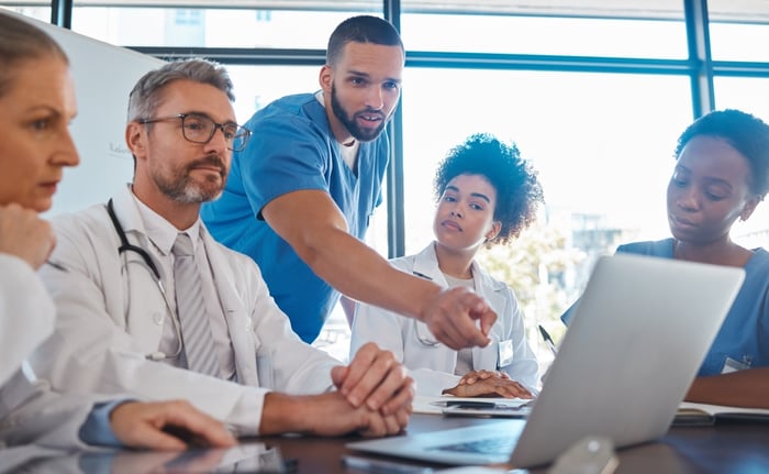 Group of doctors analyzing SEO for doctors data on a laptop, highlighting the importance of medical SEO strategies to grow their practice online