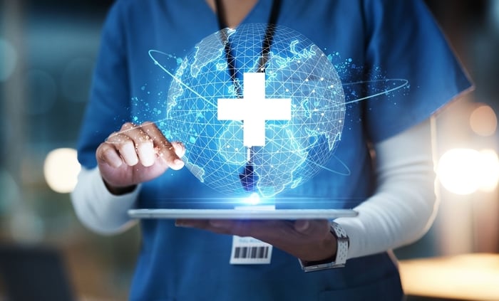 Nurse interacting with digital globe interface, representing the future of medical practice website design driven by trust, technology, and E-E-A-T principles.
