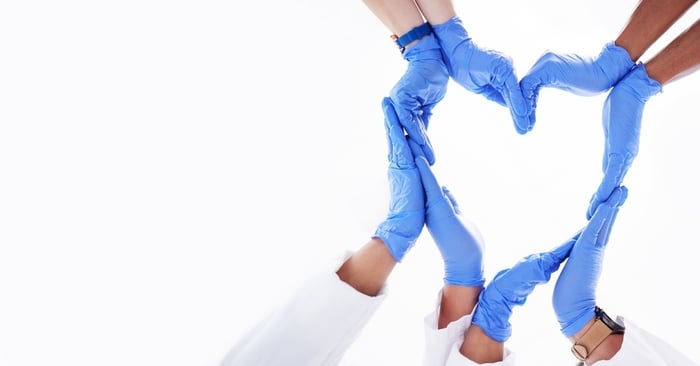 Doctor’s gloved hands forming a heart shape over a medical clipboard, representing trust, patient care, and data protection in HIPAA-compliant healthcare marketing.