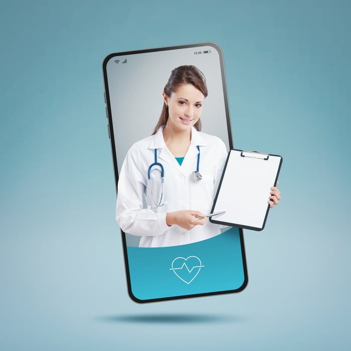 Smiling female doctor on a smartphone screen, representing modern digital marketing solutions for doctors powered by PracticeBeat.