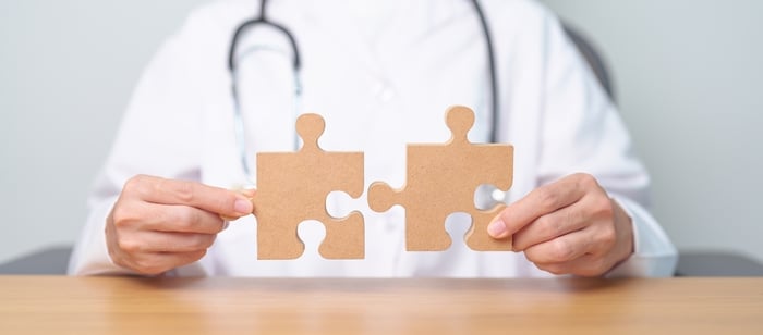 Doctor holding two puzzle pieces, symbolizing the complexity and challenges faced by healthcare practices."