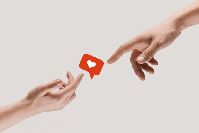 Two hands reaching toward each other with a heart notification icon between them, symbolizing connection, trust, and positive engagement.