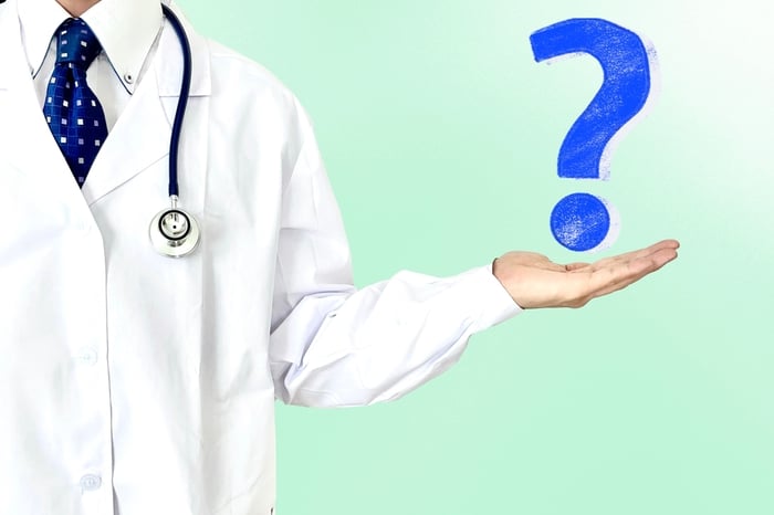 Doctor holding a question mark icon, symbolizing key actions medical practices must take now to stay competitive in AI-driven healthcare search and SEO for doctors.