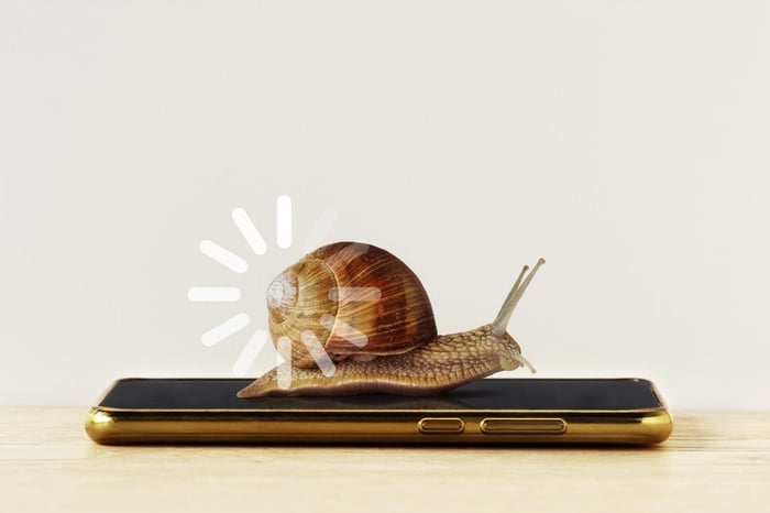 A snail with a slow loading icon on its shell is crawling on a smartphone, symbolizing extremely slow website speed or poor mobile performance for a medical or MediSpa website.