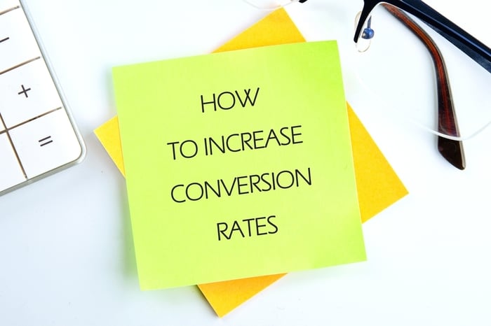 Sticky note with the phrase “How to Increase Conversion Rates” placed on a desk with glasses and a calculator — representing healthcare CRO strategies to boost patient appointments and website performance.