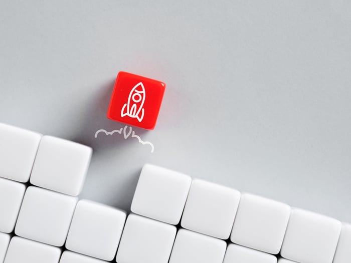 Red 3D cube with a rocket icon rising above a grid of white cubes, symbolizing innovation, growth, and launching modular content strategies for private healthcare practices.