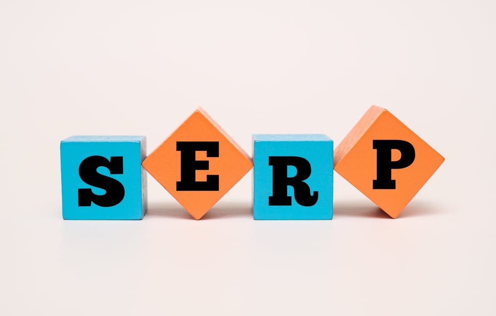 Four wooden toy blocks in blue and orange arranged in a row to spell out 'SERP,' representing the Search Engine Results Page pillars for SEO for doctors success in 2026.