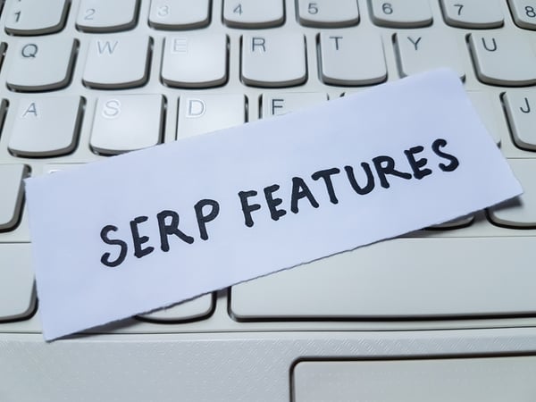 Paper with the words “SERP FEATURES” placed on a white keyboard, representing digital marketing and SEO strategies for appearing in search engine results pages (SERPs).