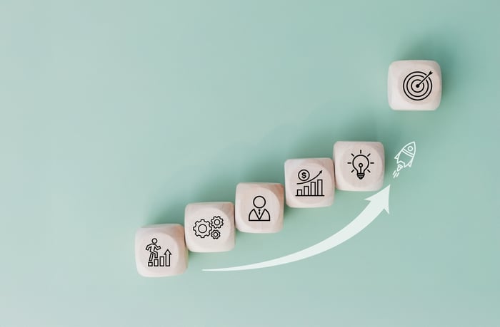 Wooden cube with a rocket icon launching upward above other wooden blocks, symbolizing strategic growth and the key benefits of modular content marketing for private practices.