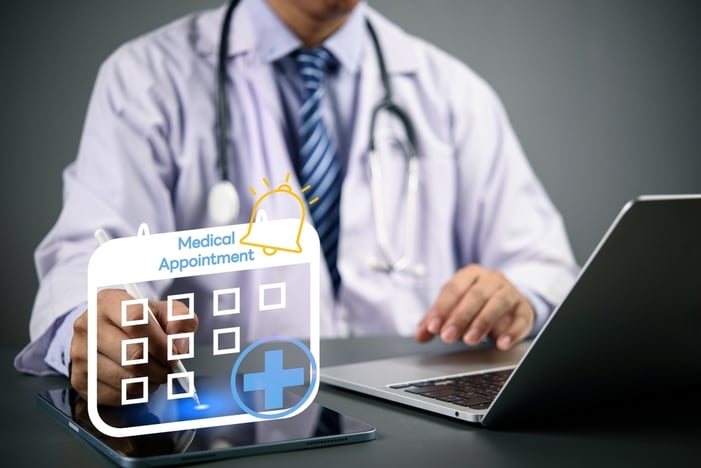 A doctor in a white coat marking a "Medical Appointment" calendar interface on a digital tablet, symbolizing the use of online scheduling and lead capture tools to reduce patient drop-offs for vascular surgery practices.