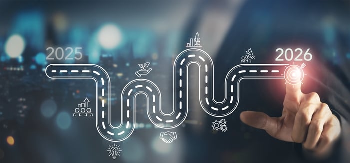 A roadmap graphic extending from 2025 to 2026, featuring a winding path with business icons (team, handshake, lightbulb, growth) and culminating in a red target/goal icon, being touched by a hand, symbolizing the strategic fixes and visibility goals for 2026 healthcare marketing.