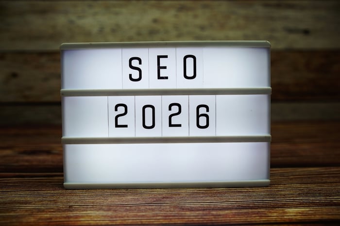 A glowing white lightbox displaying the text "SEO 2026" in bold black letters, set against a rustic wooden background, symbolizing the future-ready medical search engine optimization strategies provided by PracticeBeat.