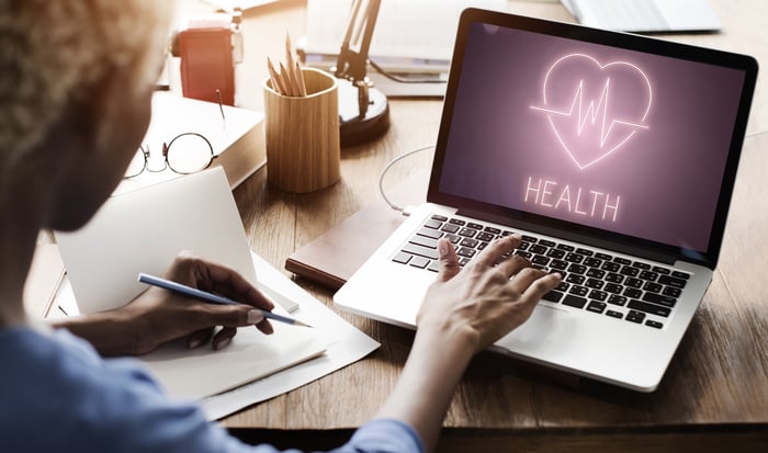 Healthcare provider using a laptop with a health icon on screen — illustrating the importance of creating digital content that informs and connects with patients.