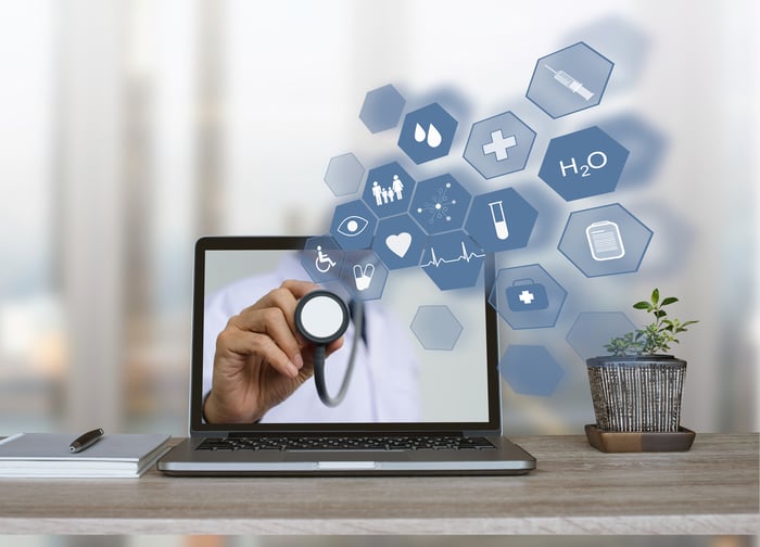 A doctor extending a stethoscope through a laptop screen, with floating healthcare icons—symbolizing digital diagnosis and the need for a user-friendly, trust-building medical website experience.